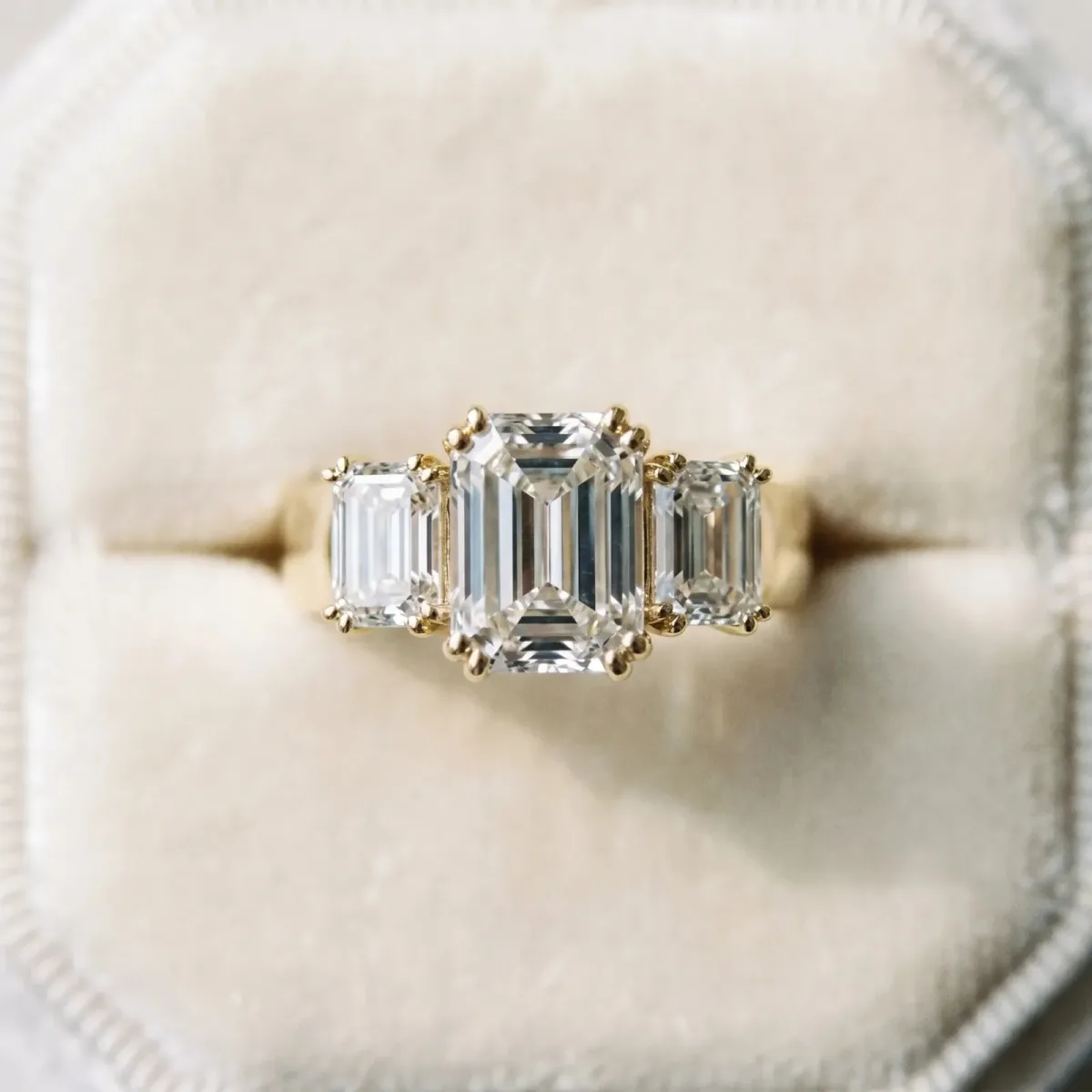 Three-Stone Emerald Cut Cut Diamond Ring with Channel Set Band and Four-Prong Setting Yellow gold