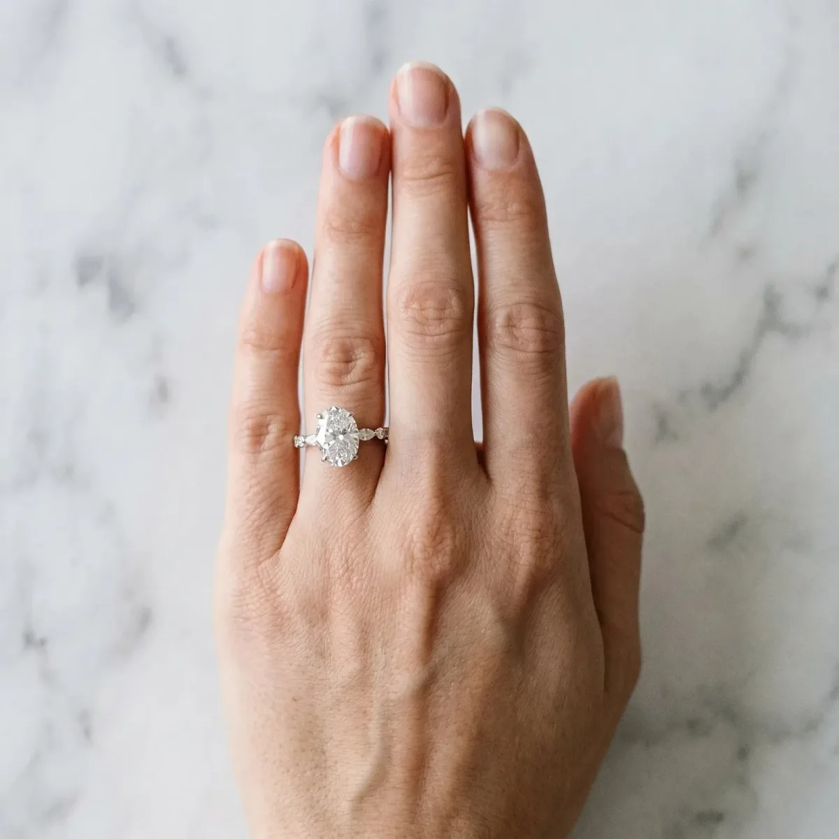 Oval Cut Diamond Ring with Marquise and Round Side Stones and Four-Prong Setting Silver
