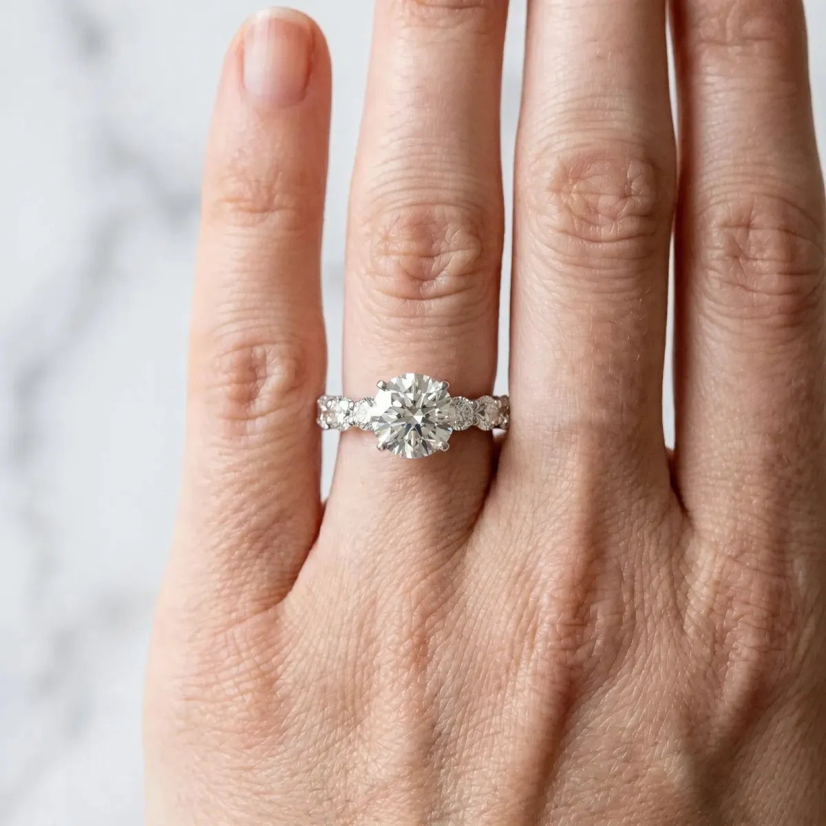 Round Cut Diamond Prong Setting with Side Stones on a Pave Band Platinum