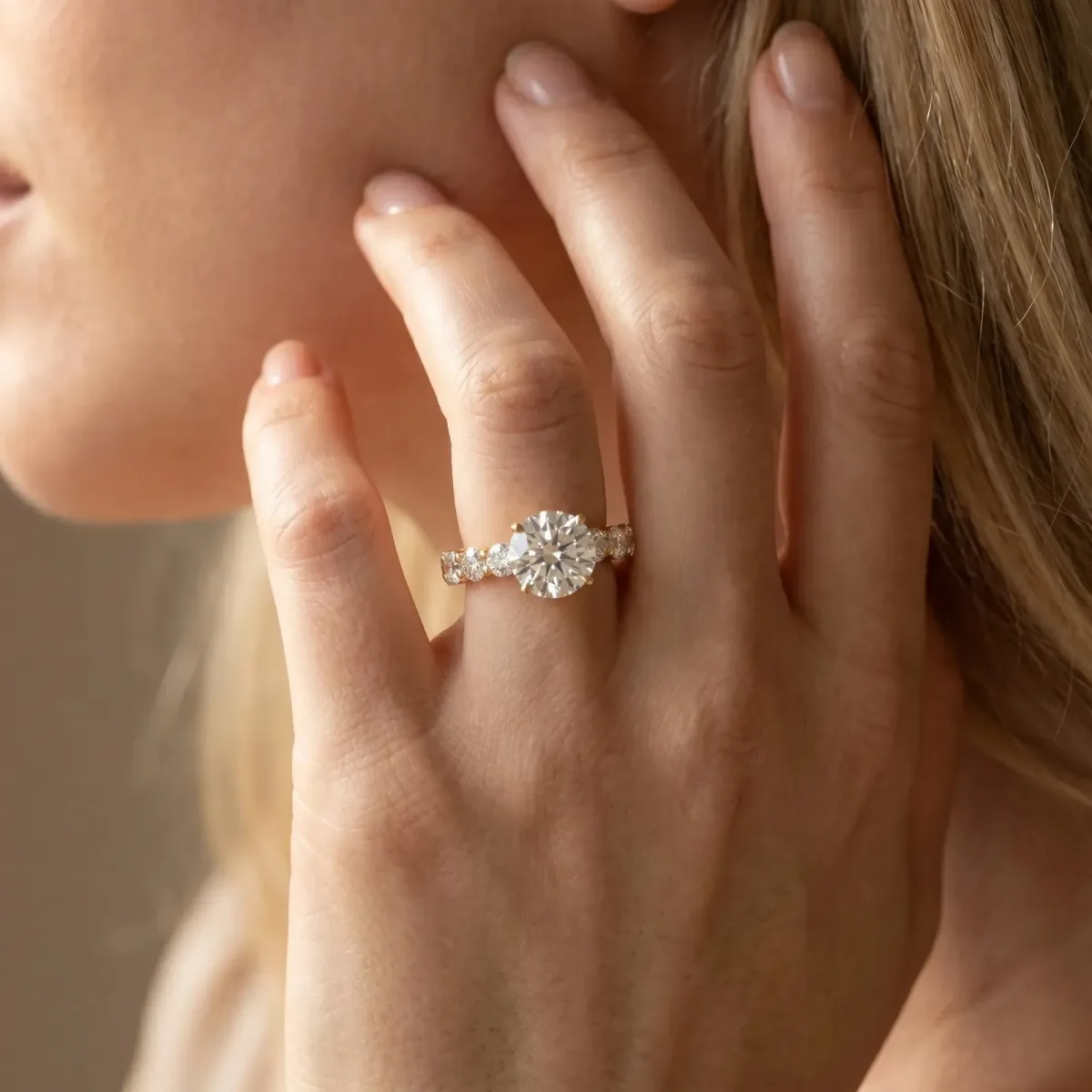 Round Cut Diamond Prong Setting with Side Stones on a Pave Band Yellow gold
