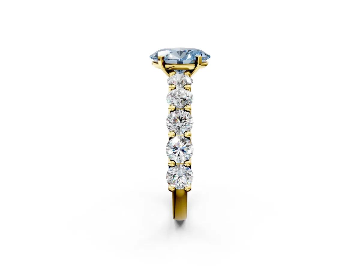 Fancy Blue Oval Cut Diamond Prong Setting with Side Stones on a Pave Band Yellow gold