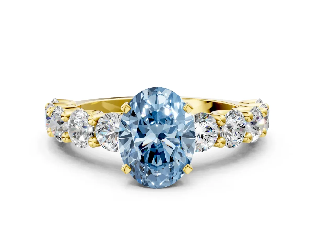 Fancy Blue Oval Cut Diamond Prong Setting with Side Stones on a Pave Band Yellow gold