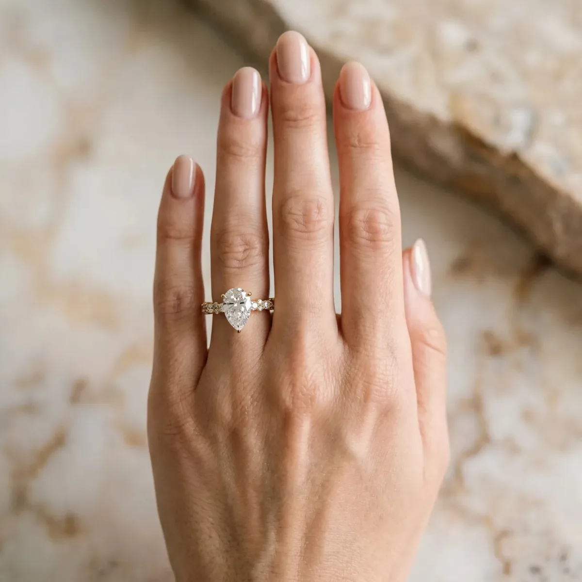 Pear Cut Diamond Side Stone Solitaire Ring with Round and Four-Prong Setting Yellow gold