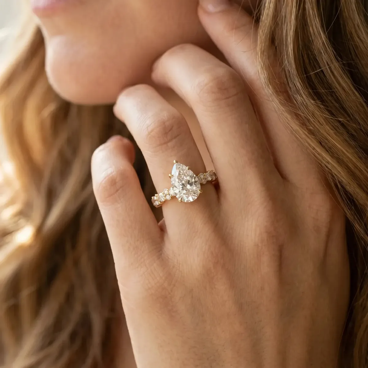 Pear Cut Diamond Side Stone Solitaire Ring with Round and Four-Prong Setting Yellow gold