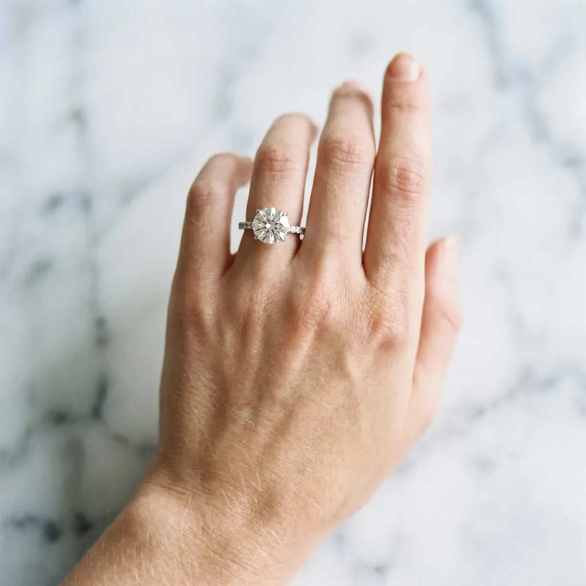 Round Cut Diamond Solitaire Engagement Ring with Pavé Band and Four-Prong Setting Silver