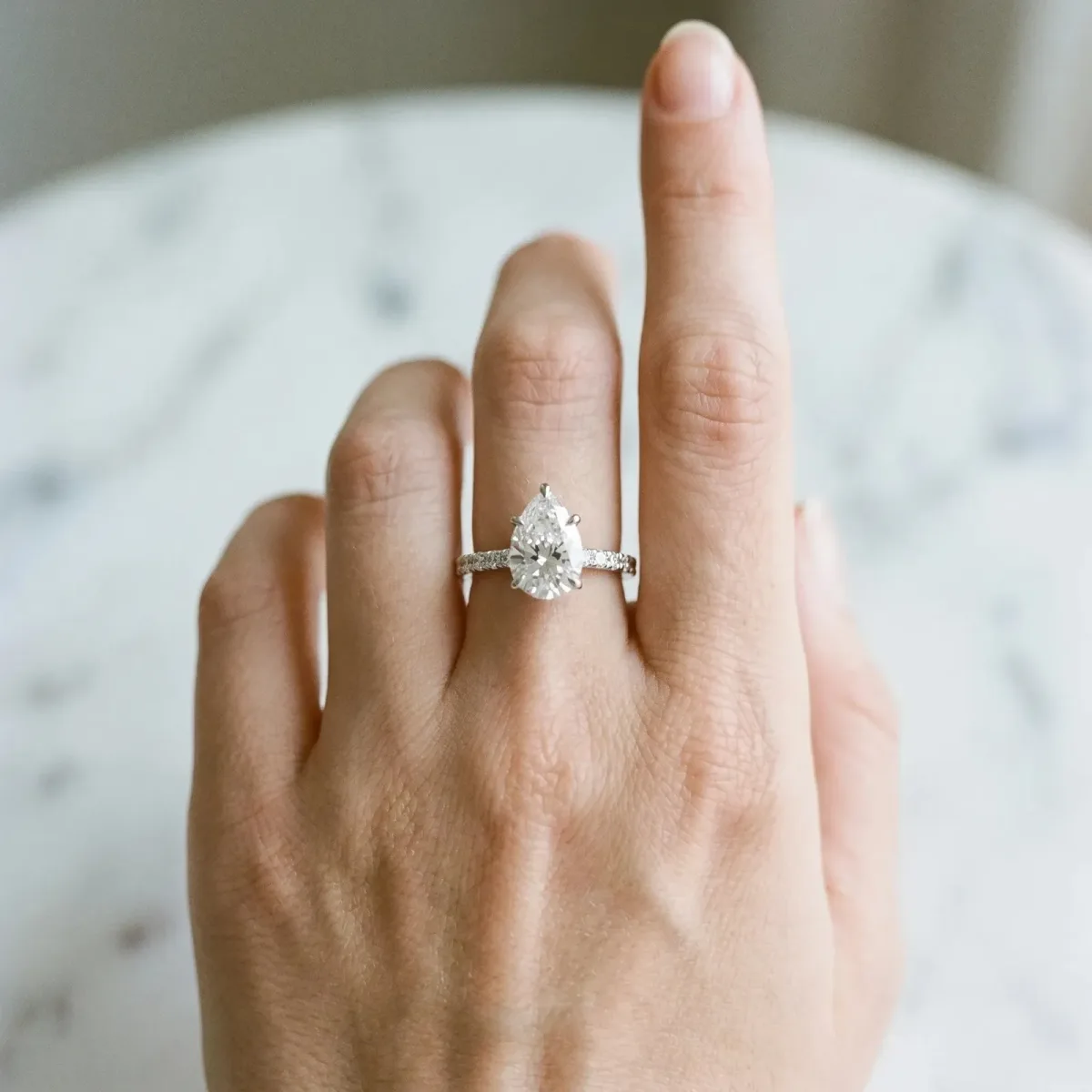 Pear Cut Diamond Solitaire Engagement Ring with Pavé Band and Four-Prong Setting Silver
